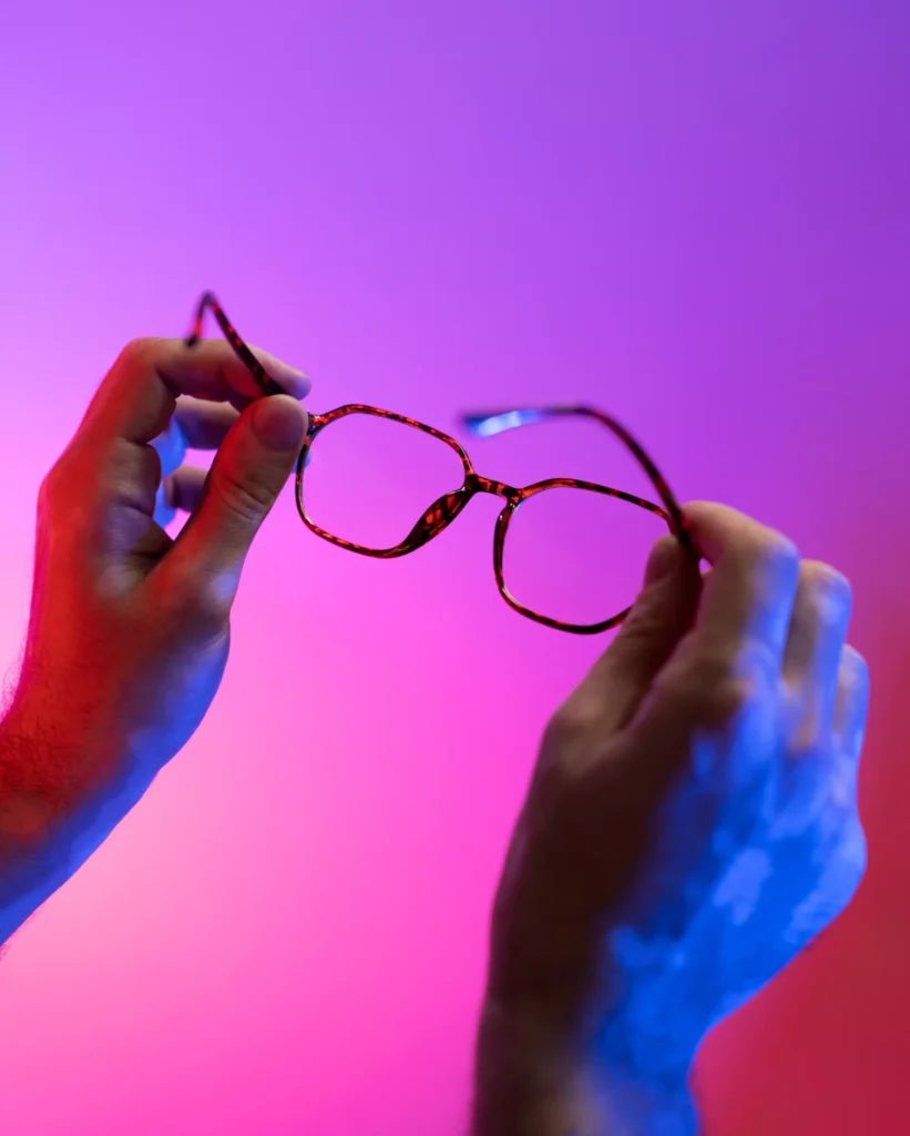 manos sosteniendo gafas sobre fondo degradado